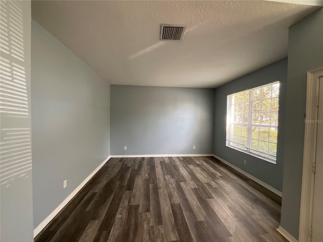 unfurnished room featuring visible vents, baseboards, a textured ceiling, and dark wood-style floors