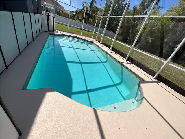 view of swimming pool featuring a fenced in pool, fence, glass enclosure, a lawn, and a patio