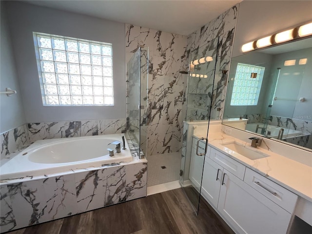 bathroom with a marble finish shower, wood finished floors, vanity, and a bath