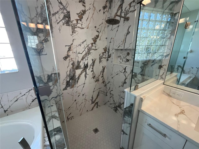 bathroom featuring a marble finish shower, vanity, tile walls, and a garden tub