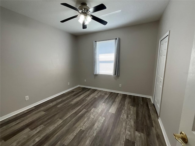 unfurnished bedroom featuring a closet, baseboards, dark wood finished floors, and a ceiling fan