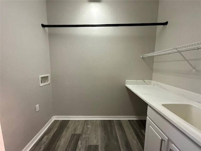 washroom featuring hookup for a washing machine, baseboards, dark wood finished floors, cabinet space, and a sink