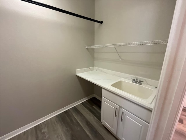 clothes washing area featuring a sink, baseboards, and dark wood finished floors