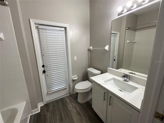 bathroom with toilet, wood finished floors, vanity, and shower / tub combination