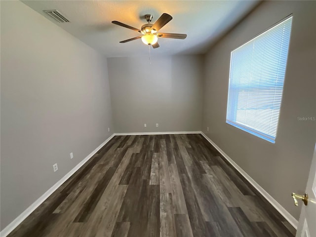 empty room featuring dark wood-type flooring, baseboards, visible vents, and ceiling fan