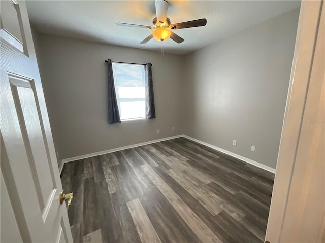 spare room with dark wood-type flooring, baseboards, and ceiling fan