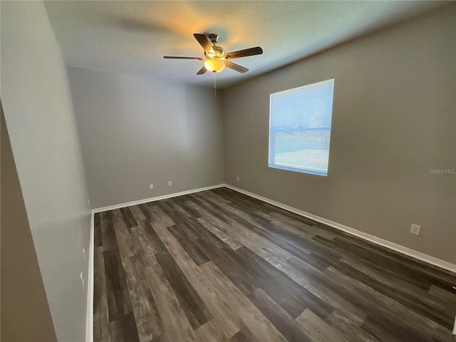 unfurnished room with baseboards, ceiling fan, and dark wood-style flooring