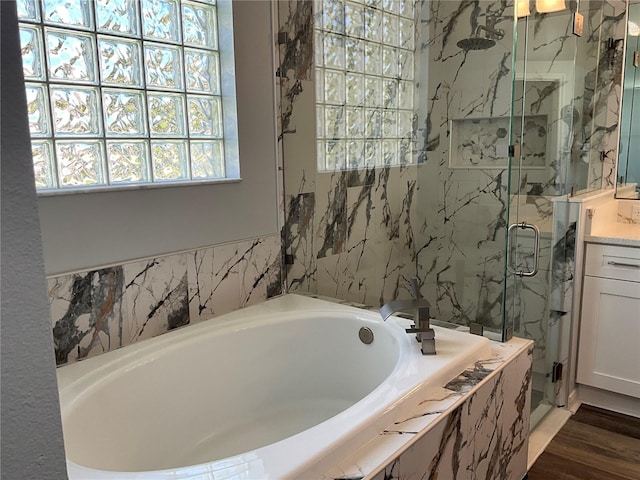 bathroom featuring a marble finish shower, vanity, a garden tub, and wood finished floors