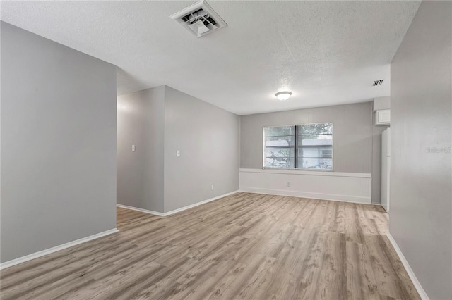 unfurnished room with visible vents, light wood finished floors, and a textured ceiling