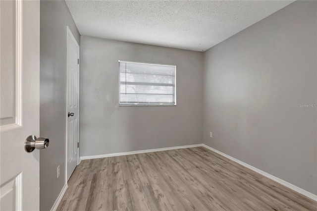 spare room with a textured ceiling, baseboards, and wood finished floors