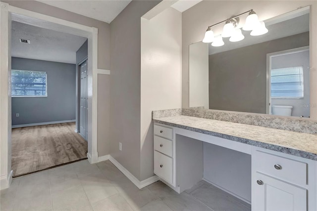 bathroom with vanity, baseboards, visible vents, tile patterned flooring, and toilet