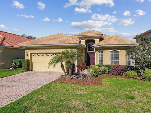 mediterranean / spanish-style house featuring stucco siding, a front lawn, decorative driveway, and a garage