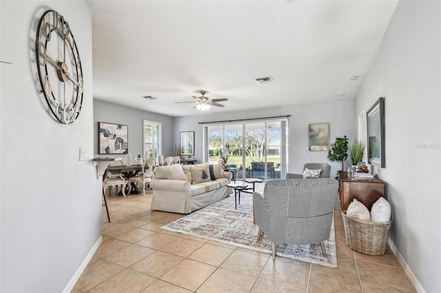 living area featuring light tile patterned floors, baseboards, visible vents, and ceiling fan