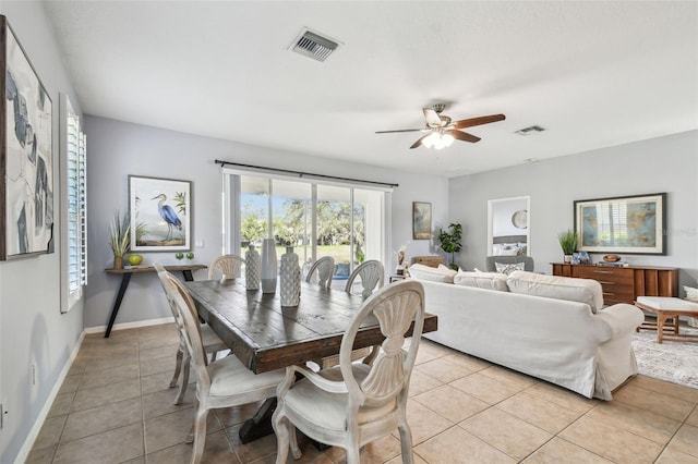 dining space with light tile patterned floors, a ceiling fan, visible vents, and baseboards