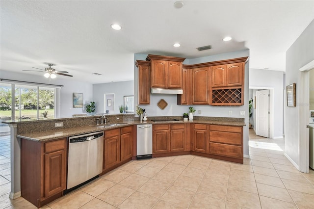 kitchen featuring visible vents, under cabinet range hood, stainless steel dishwasher, dark stone counters, and a peninsula