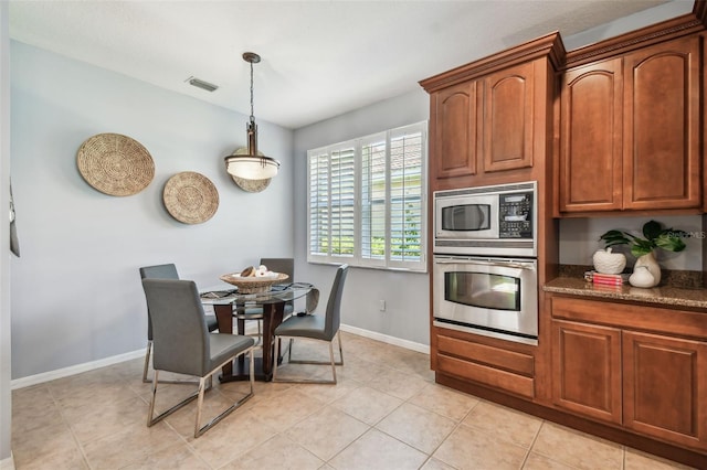 kitchen with visible vents, baseboards, pendant lighting, dark stone counters, and stainless steel appliances