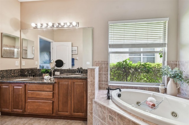 bathroom with double vanity, a tub with jets, tile patterned floors, and a sink