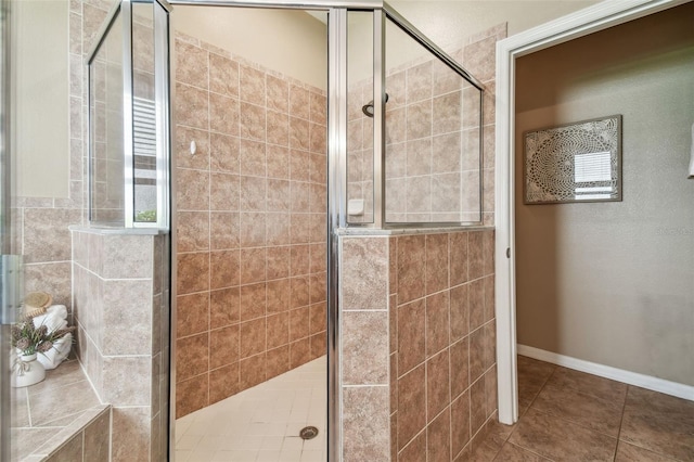 full bath featuring tile patterned floors, a stall shower, and baseboards