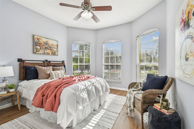 bedroom featuring baseboards, multiple windows, and wood finished floors