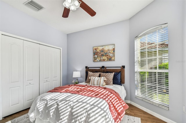 bedroom featuring visible vents, baseboards, wood finished floors, a closet, and a ceiling fan