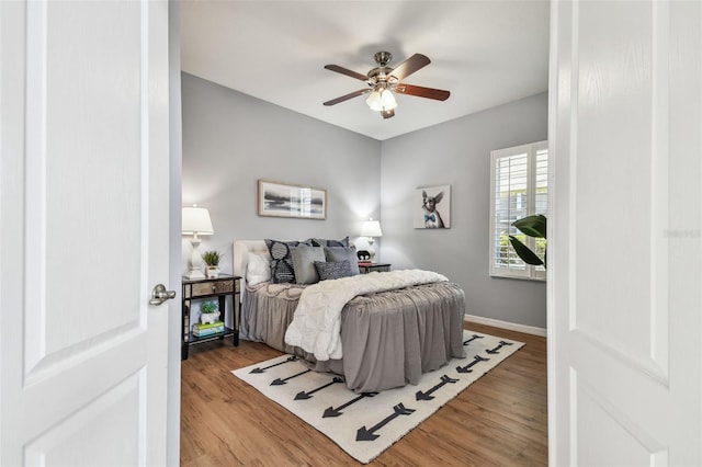 bedroom with ceiling fan, baseboards, and wood finished floors