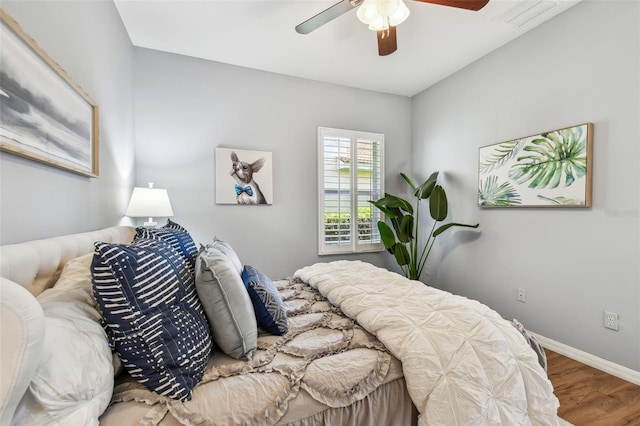 bedroom featuring visible vents, a ceiling fan, baseboards, and wood finished floors