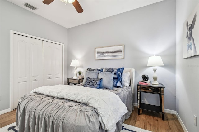 bedroom featuring a closet, visible vents, baseboards, and wood finished floors