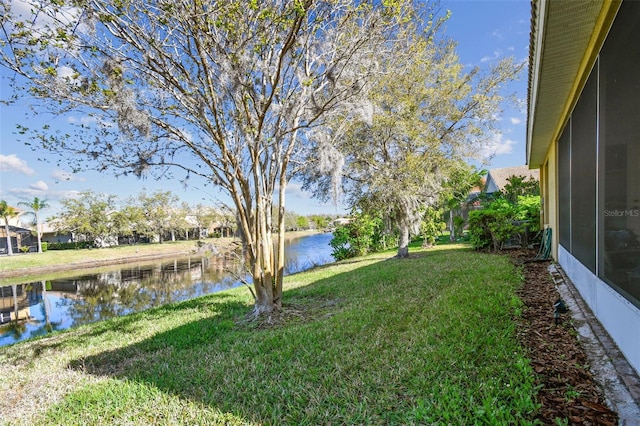 view of yard featuring a sunroom and a water view