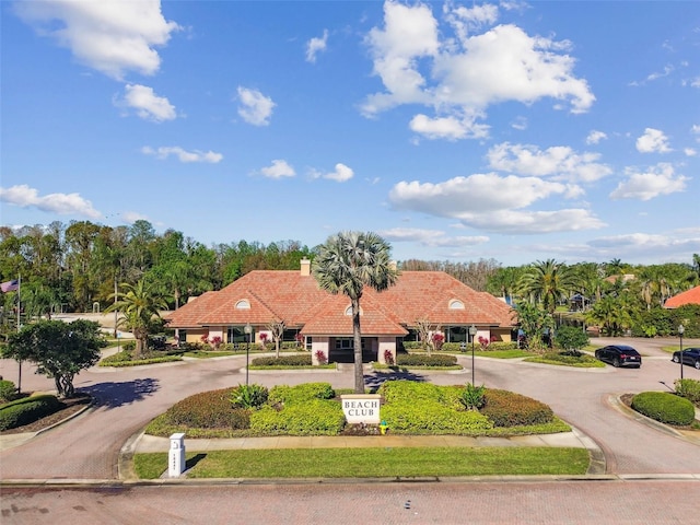 view of front facade featuring a tile roof, a chimney, and curved driveway