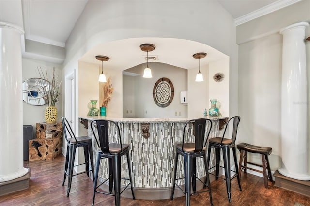 bar featuring dark wood-style floors, bar, ornate columns, and ornamental molding