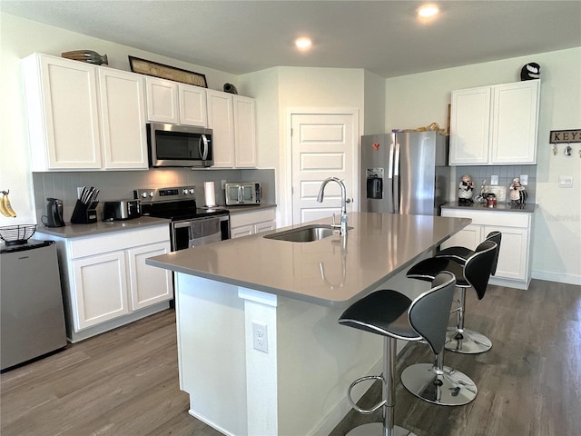 31888 Treasure Dock Isle, Wesley Chapel, FL 33545 - kitchen featuring tasteful backsplash, white cabinets, a sink, appliances with stainless steel finishes, and wood finished floors