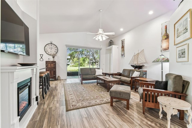 living area featuring ceiling fan, lofted ceiling, recessed lighting, light wood-style floors, and a glass covered fireplace