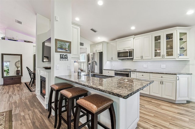 kitchen featuring visible vents, a breakfast bar, lofted ceiling, stainless steel appliances, and a sink