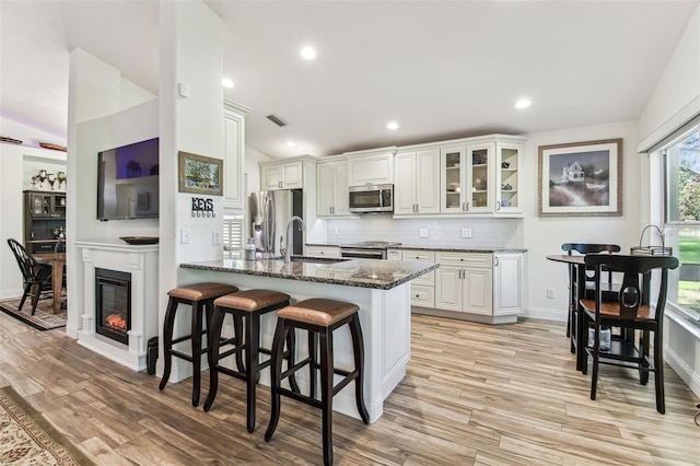 kitchen with lofted ceiling, a sink, stainless steel appliances, a kitchen breakfast bar, and tasteful backsplash