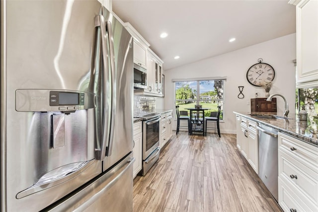 kitchen with white cabinets, appliances with stainless steel finishes, lofted ceiling, and a sink