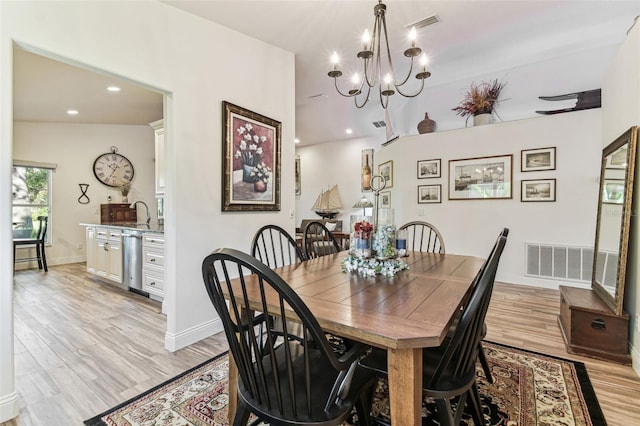 dining area with light wood-style flooring, baseboards, visible vents, and a chandelier