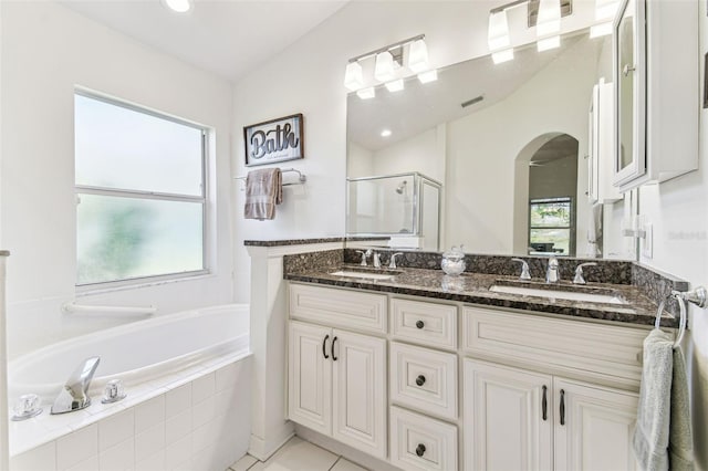 full bath featuring a shower stall, a garden tub, double vanity, and a sink