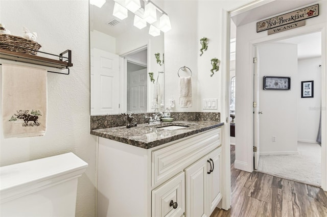 bathroom featuring toilet, vanity, baseboards, and wood finished floors