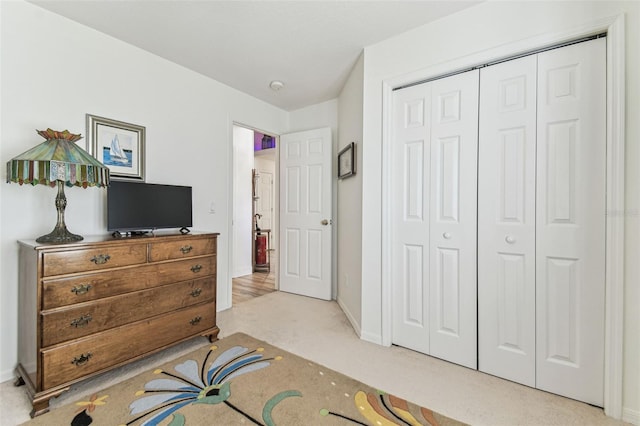 bedroom featuring light colored carpet, a closet, and baseboards