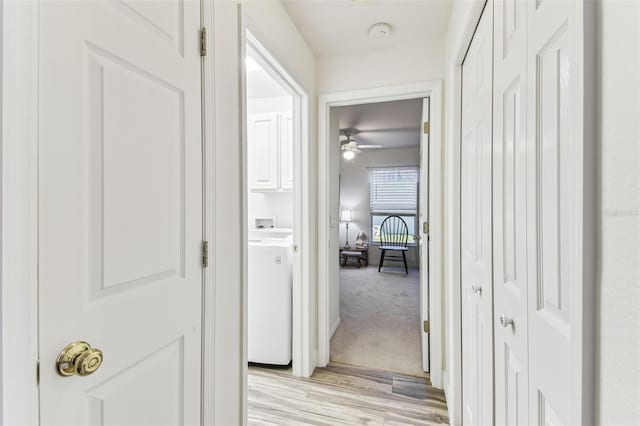 corridor with washer / dryer and light colored carpet