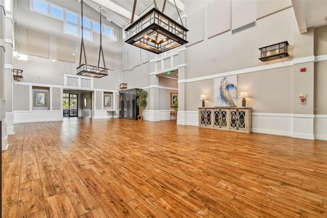 unfurnished living room featuring hardwood / wood-style floors, a decorative wall, and a high ceiling