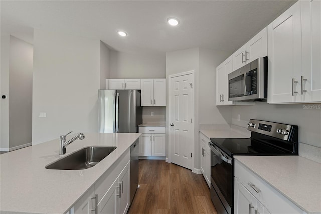 kitchen featuring dark wood finished floors, light countertops, appliances with stainless steel finishes, white cabinetry, and a sink