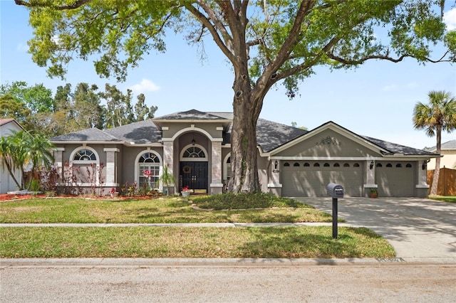 view of front of home with stucco siding, a front lawn, concrete driveway, and an attached garage