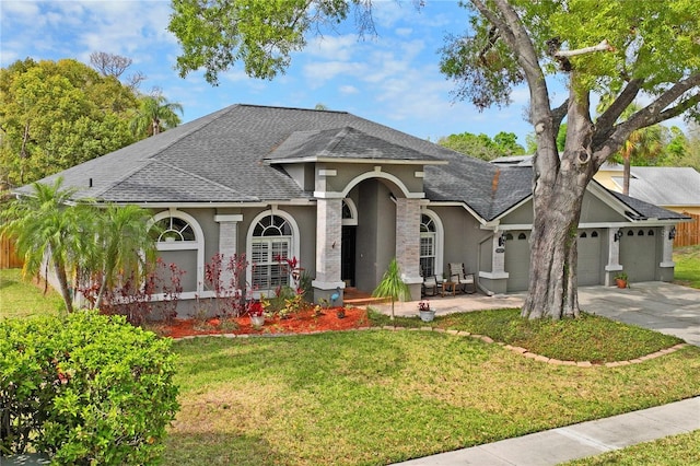 view of front of house with stucco siding, driveway, a front lawn, roof with shingles, and a garage