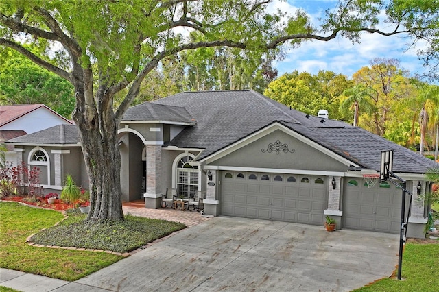 view of front of property with stucco siding, an attached garage, concrete driveway, and roof with shingles