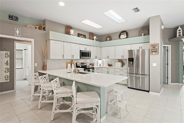 kitchen with a breakfast bar, a peninsula, light countertops, and stainless steel appliances