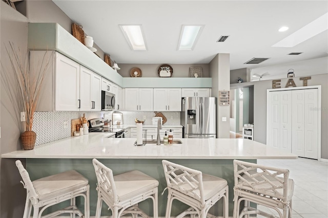 kitchen featuring a peninsula, light countertops, visible vents, and stainless steel appliances