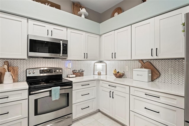 kitchen with decorative backsplash, white cabinets, light tile patterned floors, and stainless steel appliances