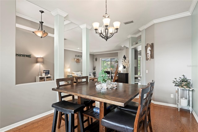 dining area featuring a notable chandelier, wood finished floors, visible vents, and ornamental molding