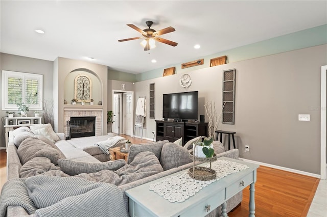 living area with wood finished floors, recessed lighting, a fireplace, baseboards, and ceiling fan